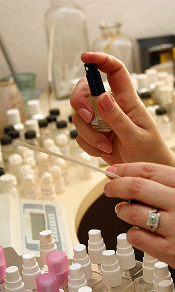Woman spraying fragrance sample on a test strip.