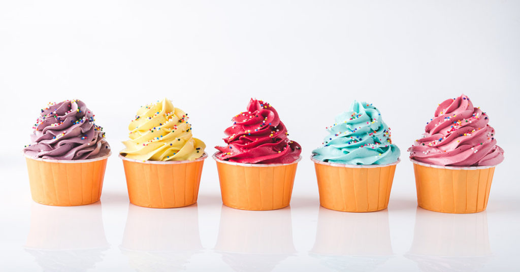 Brightly colored frosting cups with rainbow sprinkles. 